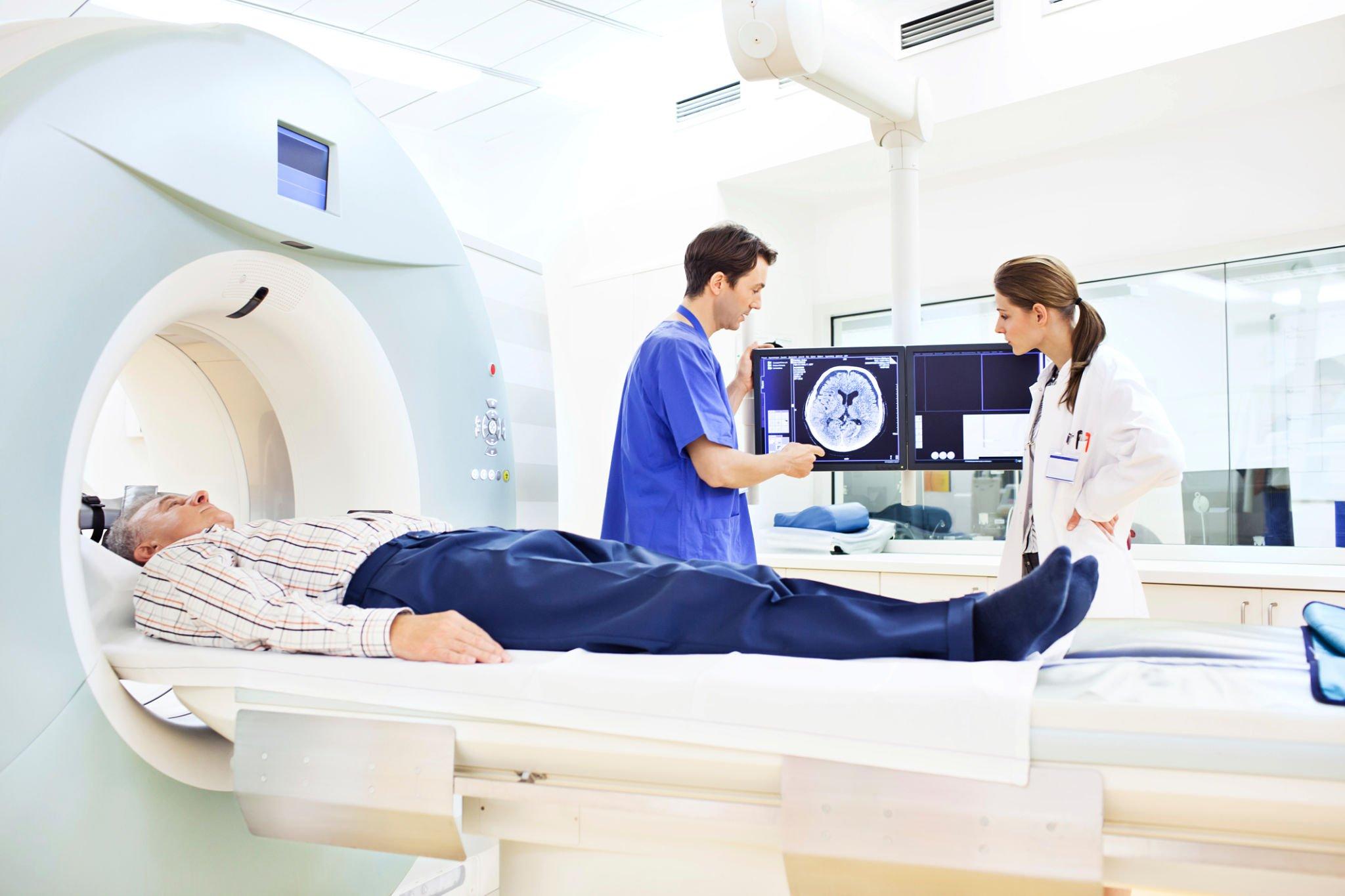 Two doctors scanning a patient's body through MRI scanning machine image